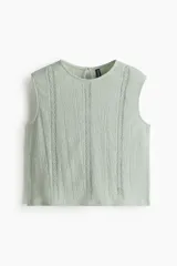 Blusa corta sin mangas en tejido de efecto arrugado, color verde menta, con inserciones de encaje en el frente y escote redondo. Cuenta con una abertura de cerradura con botón en la nuca y bajo recto.