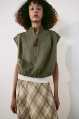 Falda midi de tiro alto, con estampado de cuadros en tonos beige y marrón, costuras marcadas y cierre lateral con cremallera oculta.