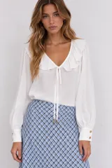 Blusa blanca de manga larga con escote en V y cuello con volados. Cuenta con lazos para atar en el pecho y puños anchos con botones dorados.