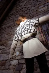 Saco tejido de punto con diseño de guarda inca en la parte superior. Presenta bolsillos frontales con detalles de tiras de cuero y flecos. De corte recto y largo medio, con terminaciones en tejido acanalado.