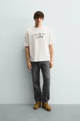 Camiseta de corte relajado confeccionada en algodón, con cuello redondo, manga corta y estampado de texto en contraste en el frente.