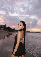 Vestido corto de tejido de punto color beige, con escote profundo tipo halter y falda con volados en el frente.