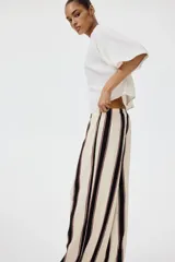 Pantalón de punto de corte holgado con piernas amplias y tiro alto, cintura elástica con cordón de ajuste y diseño a rayas verticales en tonos blanco, negro y marrón.