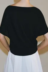 Top de punto negro con diseño holgado, escote bote y mangas cortas estilo murciélago, con ribete ancho en la cintura.