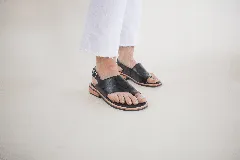 Sandalias de cuero negro con tira entre los dedos, talón descubierto y hebilla lateral.
