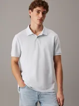 Chomba celeste de piqué de algodón, corte regular, cuello tradicional, cartera de botones, bajo con aberturas laterales y logo bordado en el pecho.