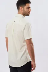 Camisa lisa de algodón azul marino, de manga corta, con cuello camisero, cierre frontal de botones y un bolsillo aplicado en el pecho.