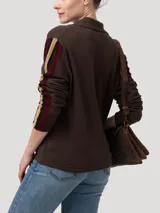 Sweater de punto color marrón con cuello camisero y cierre frontal de botones. Presenta detalles de tejido calado en las mangas con franjas laterales en contraste y terminaciones en crochet en el cuello y la tapeta.