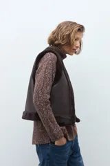 Chaleco reversible de corte recto, con un lado de cuero sintético color chocolate y el otro lado de piel sintética al tono. Presenta cuello redondo y diseño sin mangas.