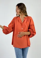 Blusa color naranja con escote en V, mangas 3/4 con detalle de crochet y cierre frontal con botones.