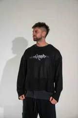 Buzo de tejido de punto fino en color negro, con diseño de cuello redondo y corte holgado. Presenta un estampado gráfico estilo gótico en el centro del pecho.