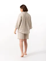 Camisa unisex de lino con mangas tres cuartos, cuello clásico, cierre frontal con botones y un bolsillo aplicado en el pecho.