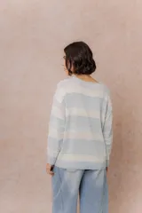 Buzo de tejido liviano con diseño de rayas horizontales en tonos amarillo manteca y blanco, cuello redondo y mangas largas con puños tejidos.
