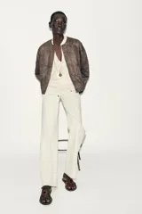 Chaqueta bomber color marrón con cuello redondo, manga larga con puño elástico y cierre frontal de cremallera metálica. Presenta un diseño de bordados florales en relieve por toda la prenda y bolsillos delanteros de vivo.