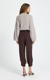 Pantalon de corte holgado color marrón, con cintura elástica ajustable mediante cordón, bolsillos laterales y puños abotonados en el bajo.