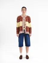 Cardigan tejido de punto jacquard en tonos bordó y rojo con rayas, de corte oversize, cuello redondo y cierre frontal con botones carey. Presenta detalles bordados en contraste y monograma en la espalda.
