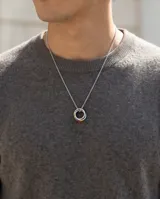 Collar de acero con dije compuesto por tres aros entrelazados, uno de ellos con detalle de esmalte multicolor. Cadena de eslabones finos.