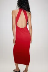 Vestido largo de corte fluido con cuello halter y espalda descubierta. Presenta un detalle de drapeado lateral y bajo recto.