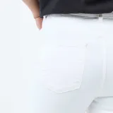 Pantalón jean blanco de corte super skinny, tiro alto con cierre de múltiples botones visibles y confeccionado en tejido elastizado.