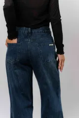 Jean de tiro alto con corte wide leg y pierna amplia. Confeccionado en denim rígido de lavado azul clásico, cuenta con bolsillos funcionales y cierre frontal.