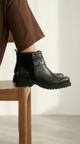 Bota corta de cuero color marrón, con diseño que combina cuero liso y sectores con textura grabada. Presenta una base robusta con taco medio y cierre lateral para facilitar el calce.