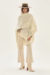 Ruana tejida en lana de cordero con diseño de sectores calados y terminación con flecos en los bordes.