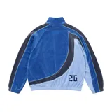 Campera deportiva de terciopelo Supreme x Umbro en color azul, con cuello alto, cierre frontal completo y bolsillos laterales. Cuenta con paneles en distintos tonos de azul y celeste, líneas curvas decorativas, y los logotipos de Umbro y Supreme bordados en el pecho junto con el escudo del Club Nacional de Football.