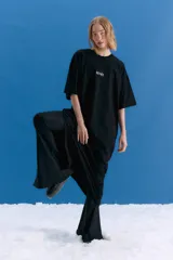 Pantalón tipo oxford de tiro medio, confeccionado en lycra con textura similar al neoprene. Presenta un corte ajustado en la parte superior que se ensancha hacia el ruedo, con tajos laterales en la botamanga y logo bordado en el frente.