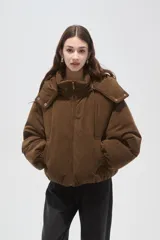 Campera puffer de color beige con cuello alto, capucha desmontable, cierre frontal y bolsillos laterales. Diseño de corte holgado con puños elásticos.