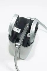 Bolso de mano mini color plateado, con doble asa corta y correa larga extraíble.