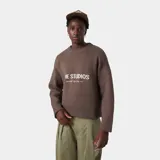 Sweater de tejido de punto color marrón oscuro, con cuello redondo y corte oversize. Presenta un estampado frontal en color blanco con el texto "EME STUDIOS" y debajo "curated by ben ice".