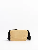 Bandolera Mishka color beige confeccionada en nylon, con correa negra ajustable de poliéster. Cuenta con cierre superior y el logo estampado en el frente.
