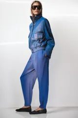Pantalón de tiro alto con diseño de volumen, pinzas en el delantero, bolsillos laterales ocultos y bolsillos traseros de vivo. Cierre frontal con cremallera y ganchos metálicos.