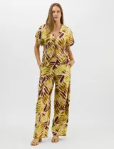 Conjunto de dos piezas confeccionado en mezcla de algodón y lino, con estampado abstracto en tonos verde y borravino. Incluye una blusa de manga corta con escote en V y cierre frontal con un botón, y un pantalón de tiro alto y pierna recta con bolsillos laterales.