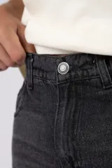 Jean mom de corte holgado color negro, confeccionado en denim de algodón con diseño clásico de cinco bolsillos y tiro medio.