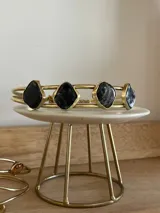 Gargantilla rígida de bronce con diseño de doble aro y piedras de nácar oscuro engarzadas en el centro.