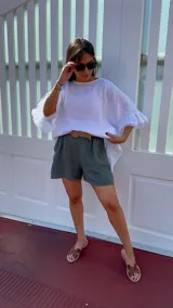 Short de lino color rojo, con cintura elástica y cinturón de rafia con hebilla circular.