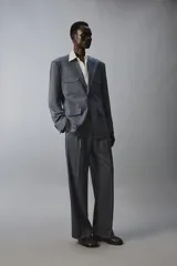 Pantalón de traje con corte flare fit, confeccionado en tejido con lana. Presenta diseño de tiro medio con pinzas frontales, bolsillos laterales y bolsillos traseros de vivo. Cierre frontal con cremallera y botón.