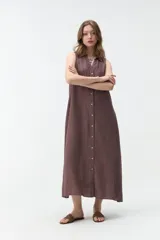 Vestido largo sin mangas de color celeste, con cuello camisero, cierre frontal con botones y bolsillos laterales.