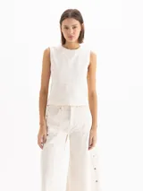Top de denim blanco marfil, sin mangas, con escote redondo y costuras pespunteadas a la vista.