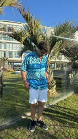 Camisa celeste con estampado geométrico en tonos azules y blancos, de manga corta y corte recto.