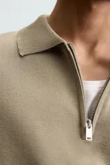 Polo de punto color verde oliva, de manga corta y corte relajado. Presenta cuello solapa con cierre frontal de cremallera.