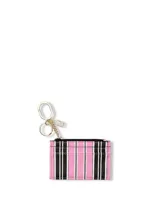 Tarjetero con llavero incorporado, diseño a rayas verticales en tonos rosado, negro y blanco, con compartimento superior con cierre de cremallera y cuatro ranuras externas para tarjetas.