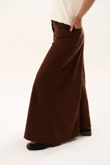 Pantalón de tiro medio con corte súper campana, confeccionado en tela de textura suave. Presenta cierre frontal con cremallera y botón, bolsillos delanteros y traseros, y costuras verticales que definen su estructura.