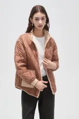 Campera acolchada de poliamida en color beige, con diseño de costuras en rombos, cuello alto, cierre frontal y bolsillos delanteros con solapa.