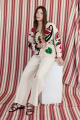 Chaqueta color crudo con bordados florales en tonos rojo, verde y negro.