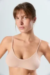 Top de estilo deportivo confeccionado en tejido seamless, con breteles finos y escote redondeado. Presenta un diseño minimalista y ajustado con el logo de la marca estampado en el bajo busto.