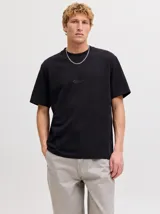 Remera negra de manga corta con cuello redondo y calce relajado, confeccionada en tejido de punto interlock con sutil estampado frontal.
