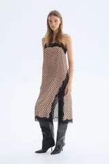 Vestido midi de satén color beige con estampado de lunares negros, breteles finos ajustables, escote recto con ribete de encaje negro, tajo lateral con detalle de encaje y bajo con terminación de encaje.