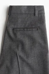 Pantalón sastrero gris oscuro con estampado a cuadros, pinzas, cierre oculto, bolsillos al bies y piernas amplias con pliegues.